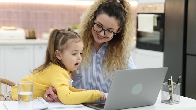Woman with her daughter working at white table in home office