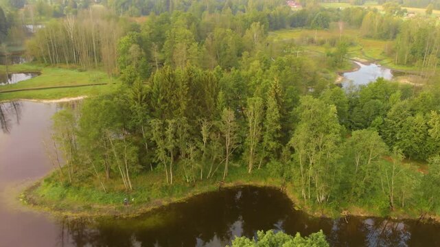 Drone footage captures the stunning natural landscape of the Kirkilai Lakes, a series of small, irregular ponds formed from karstic voids, surrounded by lush green forests and meadows in the Birzai Re