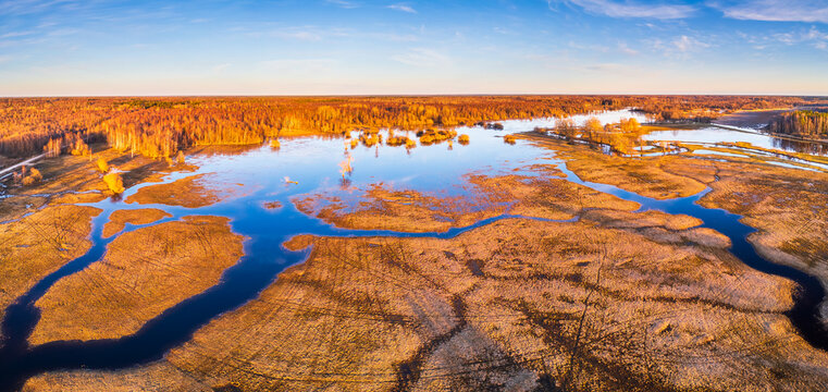 Aerial view of Soomaa National Park during the spring flood, with winding river channels cutting through golden-brown wetlands and forests in Riisa, Parnu County, Estonia.