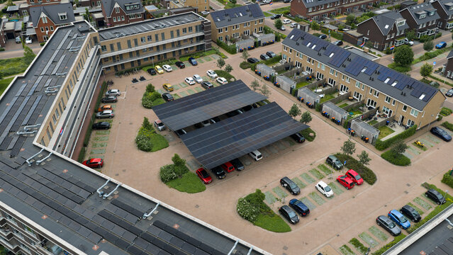 Aerial drone view of a solar carport generating renewable electricity, protecting parked vehicles and supporting electric charging and sustainable mobility.