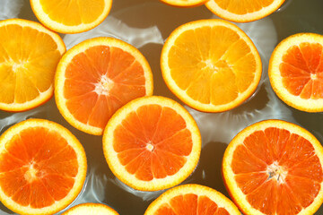 Naklejka premium Juicy orange slices floating in clean, clear rippling water.