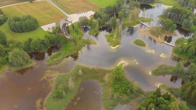 Aerial view of the unique interconnected Kirkilai karst lakes and observation tower in Biržai Regional Park, Lithuania, showcasing a scenic natural landscape with green forests and a pedestrian boardw