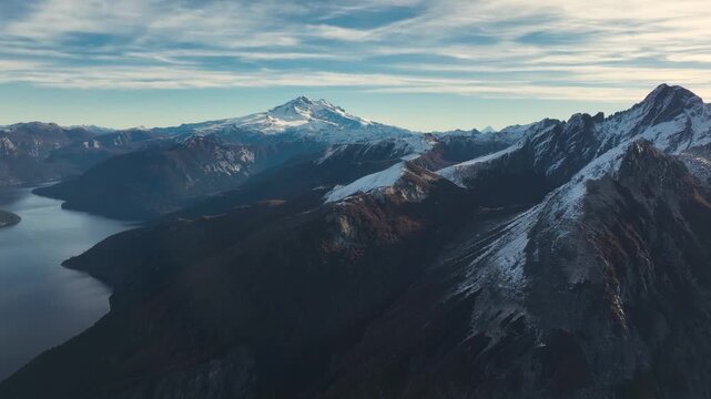 Aerial drone overlooking the snow-covered summit of Cerro Tronador with the deep waters of Brazo Tristeza branch winding through the Andean mountains, Argentina.
