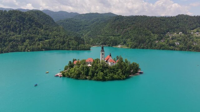 View of bled island with church and surrounding lake at midday
