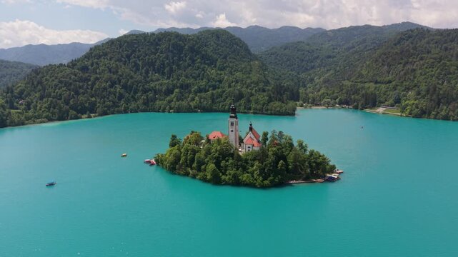 Island with church in the middle of lake surrounded by mountains in Slovenia