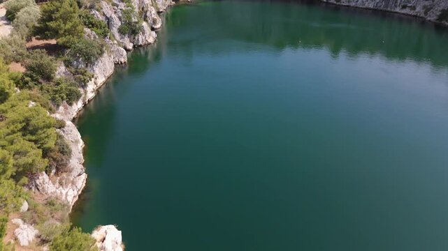 Dragon Eye Lake surrounded by cliffs and pine trees aerial Croatia