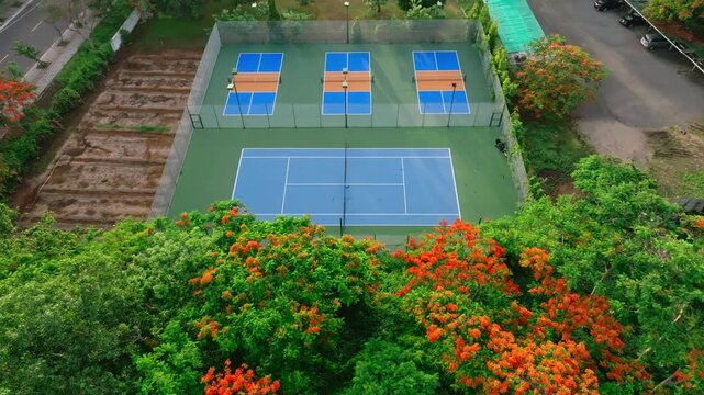 Outdoor Pickleball Courts. Sweeping views in motion of empty pickleball courts. Moving forward across several courts in a row. Public city park setting with cloudy blue Summer sky.