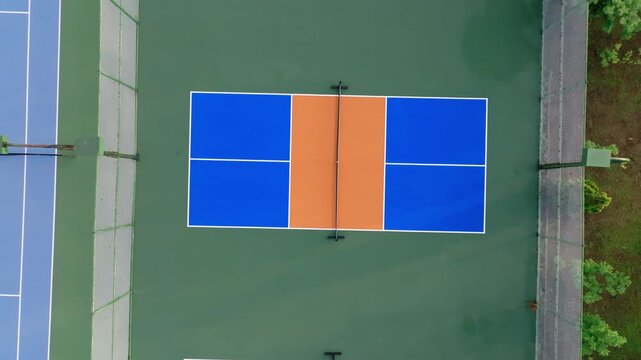 Outdoor Pickleball Courts. Sweeping views in motion of empty pickleball courts. Moving forward across several courts in a row. Public city park setting with cloudy blue Summer sky.