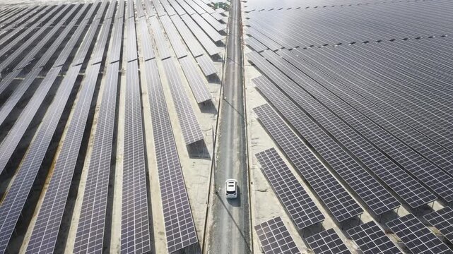 Aerial drone view of a massive solar panel farm with a white car driving in Sinan, South Korea