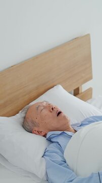 ベッドでイビキをかいて寝るシニア男性