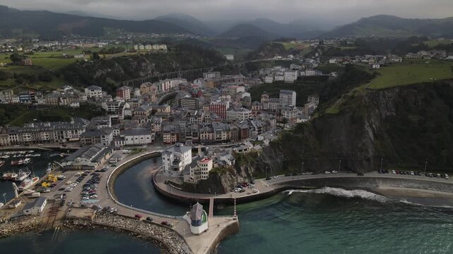 Aerial view of the picturesque town of Luarca, nestled between cliffs and the Cantabrian Sea, featuring historic buildings, a harbour, and green hills in Luarca, Asturias, Spain.