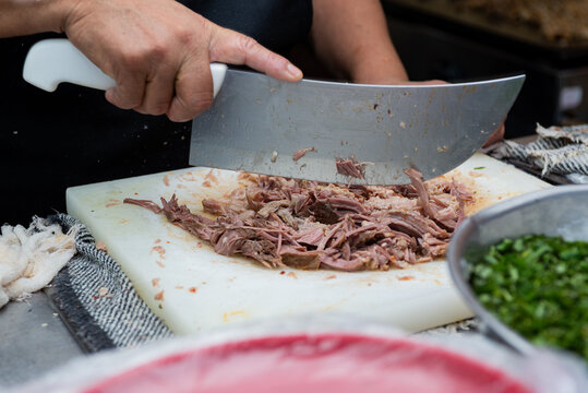 Female hands cutting meat at a taco stand. Mexican street food.