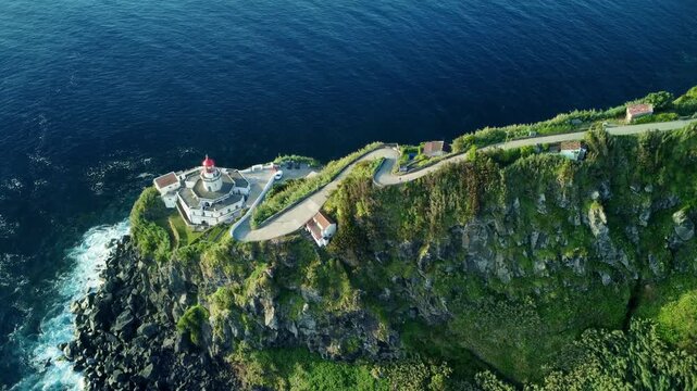 Arnel lighthouse perched on a lush green cliff in azores