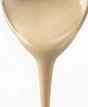 Smooth creamy beige liquid pouring from a spoon