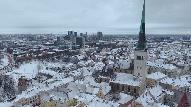 Aerial view of St. Olaf's Church surrounded by snow-covered rooftops and historic architecture in the old town of Tallinn, Harju County, Estonia.
