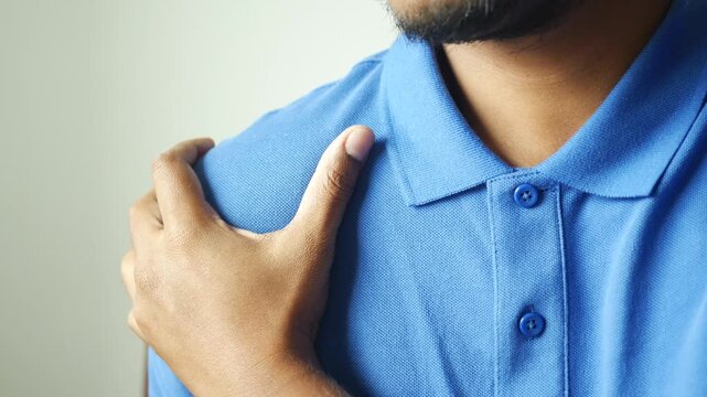A man wearing blue shirt having pain in his shoulder, close up, health and medical concept
