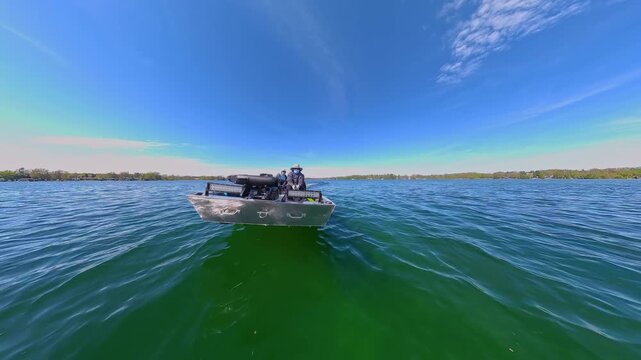 Lake Couchiching  Jon Boat speeding with trolling motor at the front and fishing accessories. Two anglers boating in Canadian lake. Front hull view of utility boat. Speed boat ride to fishing spot.