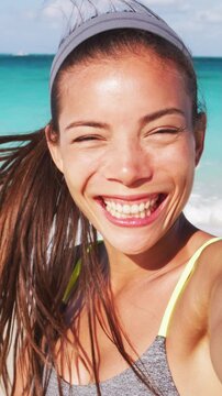 Face closeup portrait of beautiful young woman laughing having fun with on tropical beach in slow motion. Video is unretouched and model without makeup. Raw footage. Vertical video.