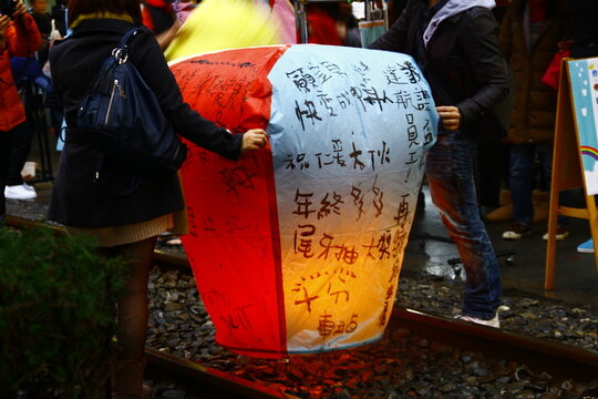 Tourists holding a traditional sky lantern with blessings on the railway tracks in Shifen.