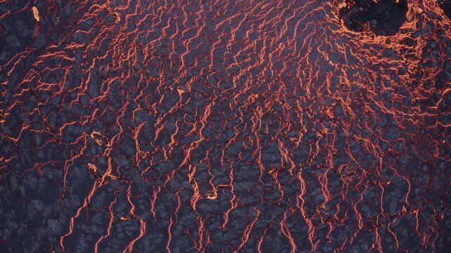 Aerial view of glowing orange magma flowing through dark cooling basalt rock formations in Grimsey, Reykjanesbaer, Iceland.