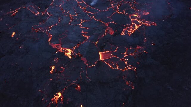 Aerial view of glowing magma flowing through dark volcanic rock during an eruption in Grimsey, Reykjanesbaer, Iceland.