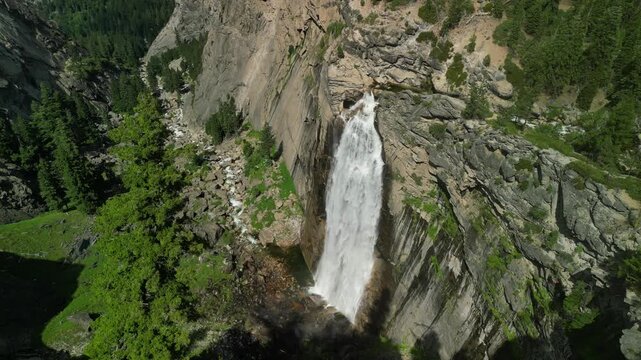 Aerial shot of Yosemite Valley featuring cascading waterfall surrounded by granite cliffs, dense forest, and dramatic mountain landscape in California&rsquo;s Sierra Nevada.