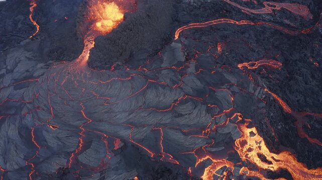 Aerial view of molten lava flowing across the dark volcanic landscape during an active eruption in Reykjanesbaer, Iceland.