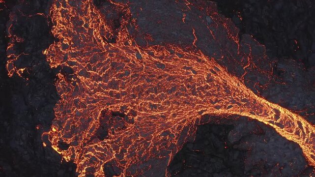 Aerial view of glowing lava flow moving across dark volcanic rock in Grimsey, Reykjanesbaer, Iceland.