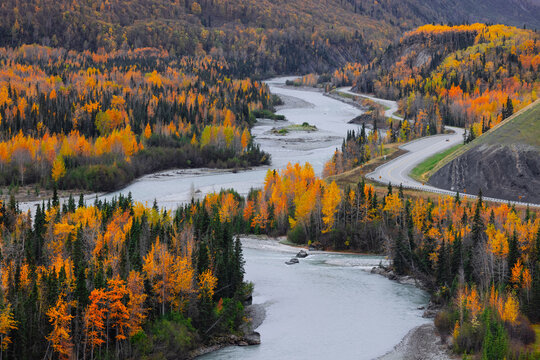 Winding river and road through autumn forest landscape