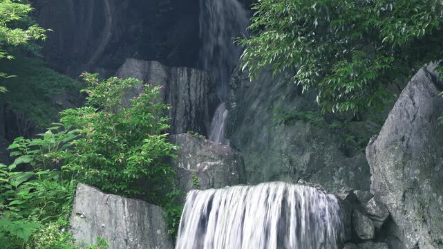 日本庭園に流れ落ちる繊細な滝と岩肌のコントラスト
