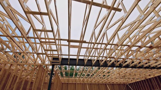 Workers install wooden beams in house structure is with ongoing construction activity.