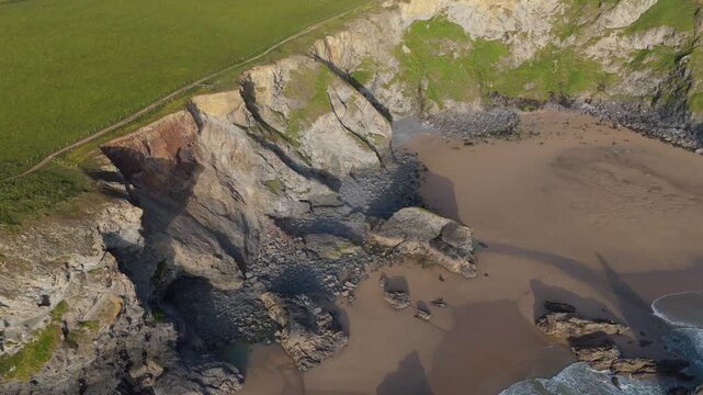 Aerial view of Pentire Steps Beach with rugged cliffs and sandy shores along the coastline of Newquay, England, United Kingdom.