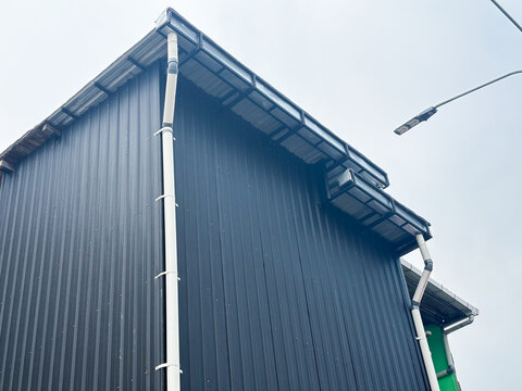 Modern Industrial Building with Black Corrugated Metal Siding and PVC Rain Gutter System