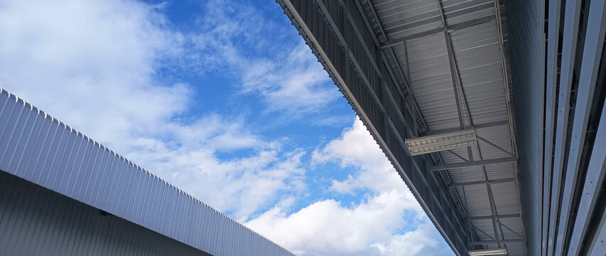 Metal sheet roof curve on blue sky. Modern construction, Metal ribbed arch span roof covering, Large building roof. not ai
