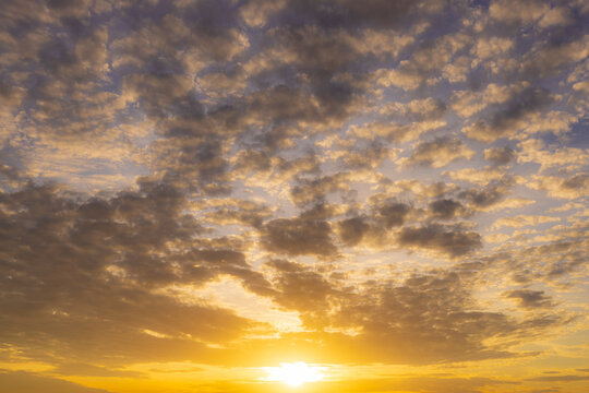 Golden Sunset Clouds in the Evening Sky,A breathtaking view of golden sunset clouds filling the sky during the late afternoon, creating a warm and peaceful atmosphere.