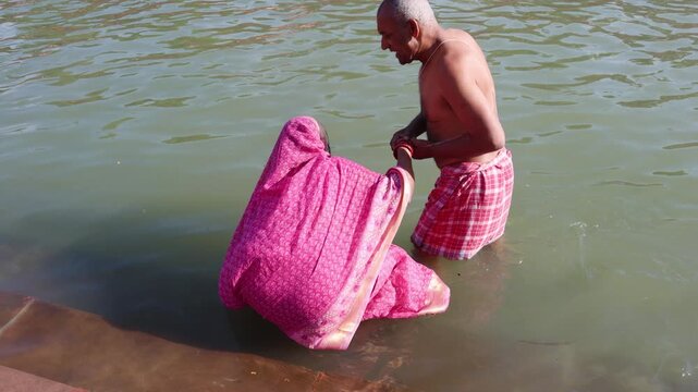 devoted elderly pair entering sacred waters during pilgrimage with mutual support
