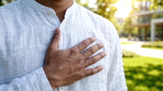 Man with hand over heart showing gratitude, appreciation or taking an oath outdoors in sunlight
