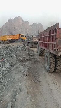 Heavy dumper trucks operating on a rocky mountain construction site