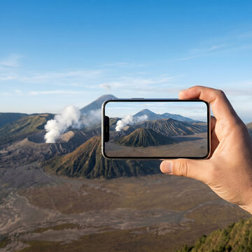Capturing Bromo volcano's majestic smoking crater with a smartphone during a breathtaking sunrise landscape view