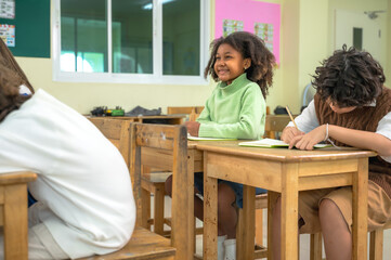 Obraz premium Diverse group of multi-ethnic elementary school students sitting and listening attentively in modern international school classroom