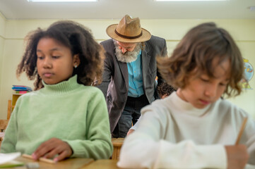 Obraz premium Diverse group of multi-ethnic elementary school students sitting and listening attentively in modern international school classroom