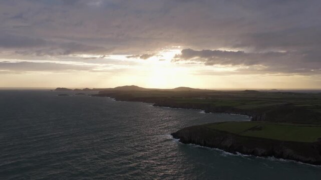 Aerial view of the sunset over the rugged Welsh Coast with green fields and cliffs in St Davids, Wales, United Kingdom.