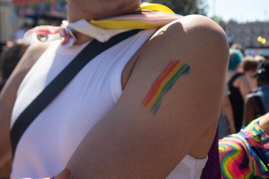 Dettaglio del braccio di una persona con strisce arcobaleno dipinte sulla pelle durante una parata per i diritti della comunit&agrave; LGBT, simbolo di orgoglio, inclusione e libert&agrave; di espressione
