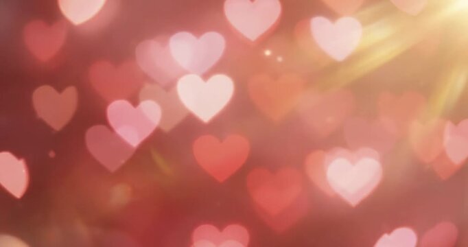 Red heart-shaped bokeh lights with soft golden sun flare, romantic abstract background for valentines day or wedding celebration.
