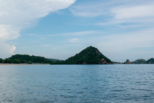 Scenic view of a unique rock formation with a green tree on top at Mandalika beach, beautiful tropical coastal landscape in Kuta Lombok, Indonesia