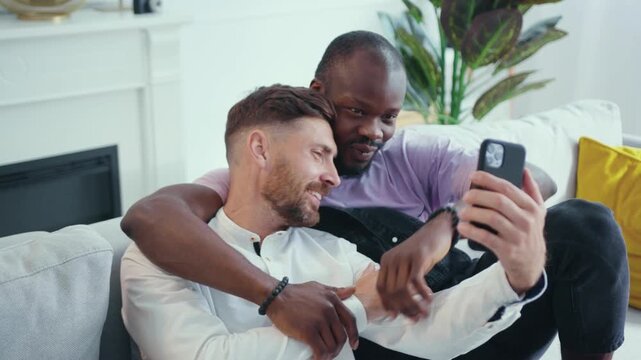 Two friends relax on a couch, share laughs, and take selfies