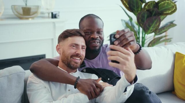 Two friends relax on a couch, taking selfies and sharing laughs