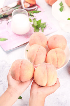 Fresh Yangshan Peaches from Wuxi China Held in Hands with Milk and Mint Leaves on White Background