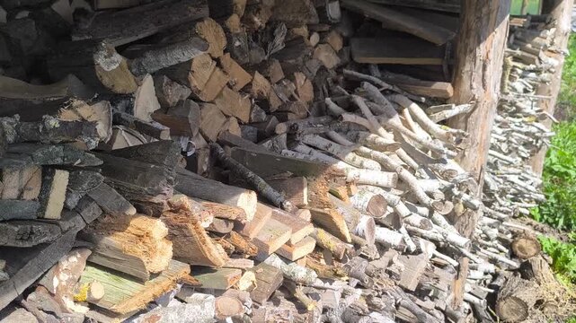 A large pile of chopped firewood and neatly stacked logs in the open air