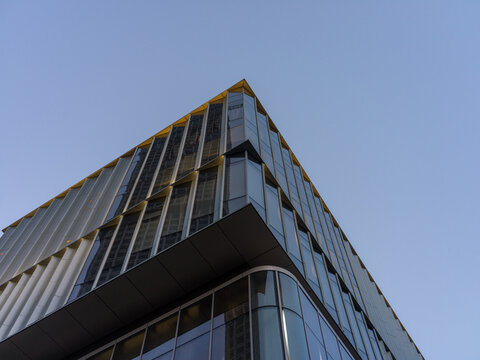 Low angle view of modern glass building corner against clear blue sky